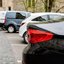 Row of at street side parked cars. View to the rear of cars - image